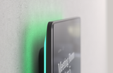 A close-up of one corner of the Humly Room Display showing the LED strip on the back of the panel, the glow from which is visible on the wall behind.